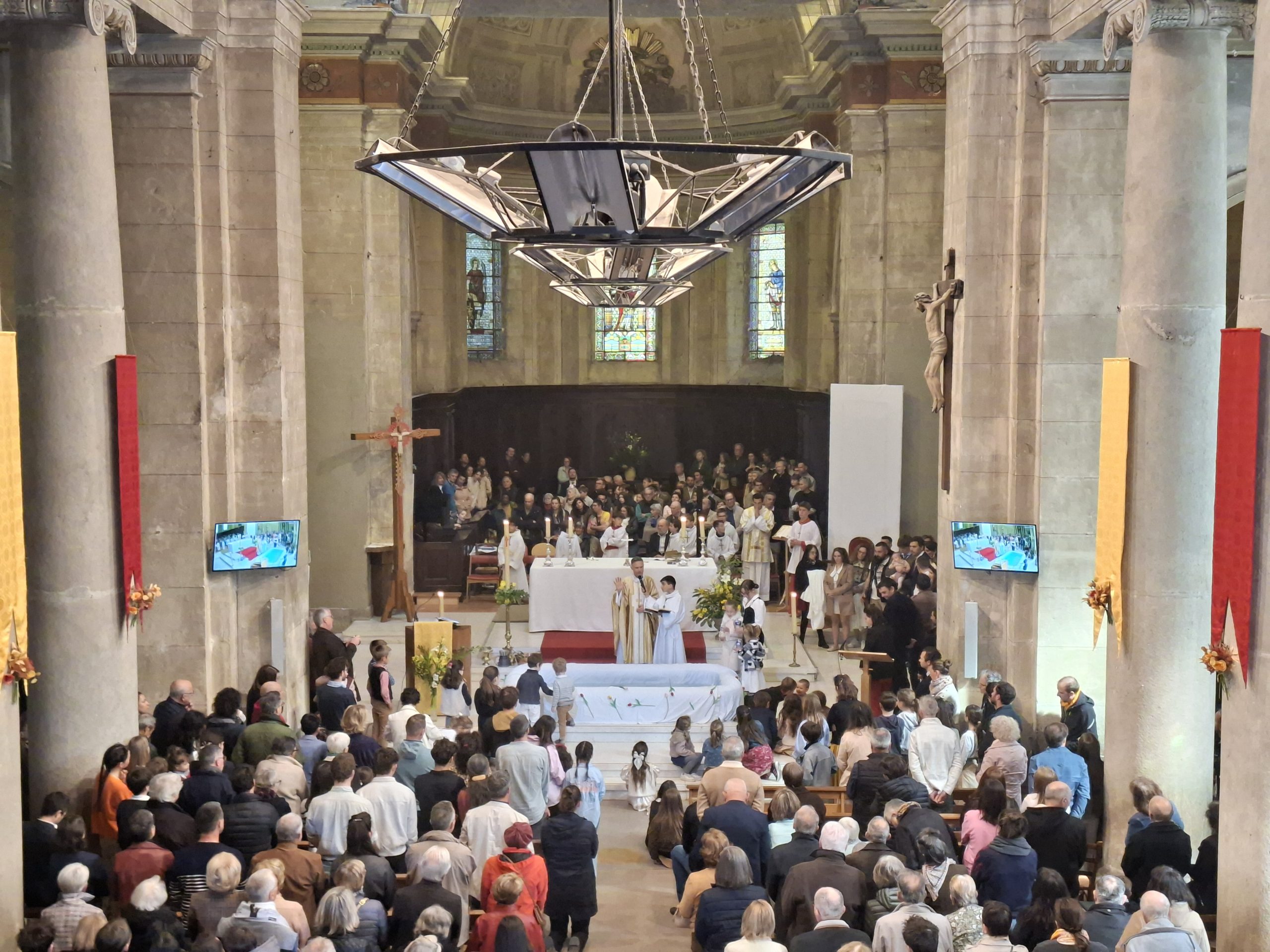 Célébration de baptêmes dans une église, avec les familles réunies autour du baptistère.